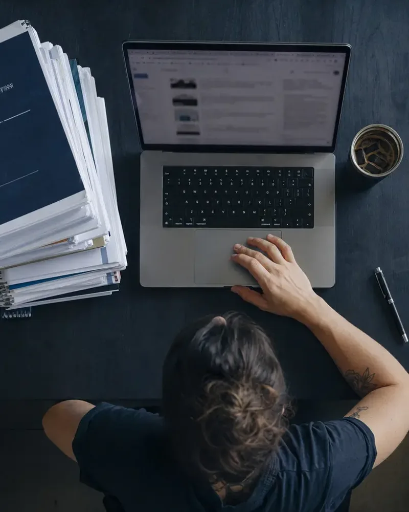 Pilha de apostilas de cursos e notebook com muitas abas abertas, sem direção